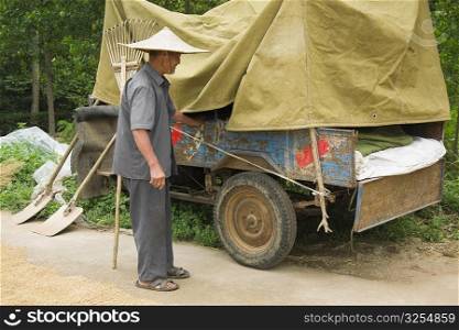 Farmer standing beside a vehicle trailer, Zhigou, Shandong Province, China