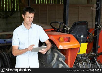 Farmer Standing Next To Tractor Using Digital Tablet