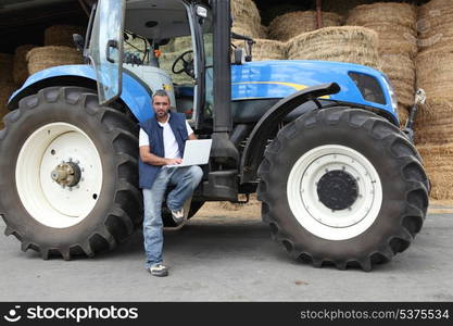 Farmer using a laptop on his tractor