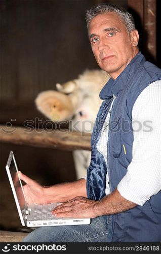 Farmer using his laptop in the barn