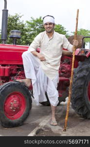 Farmer with stick and leg on tractor wheel