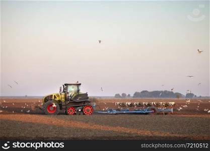farmer with tractor plows field in late summer on countryside of lower saxony in germany under blue sky