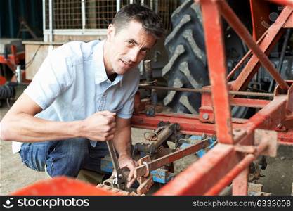 Farmer Working On Agricultural Equipment In Barn