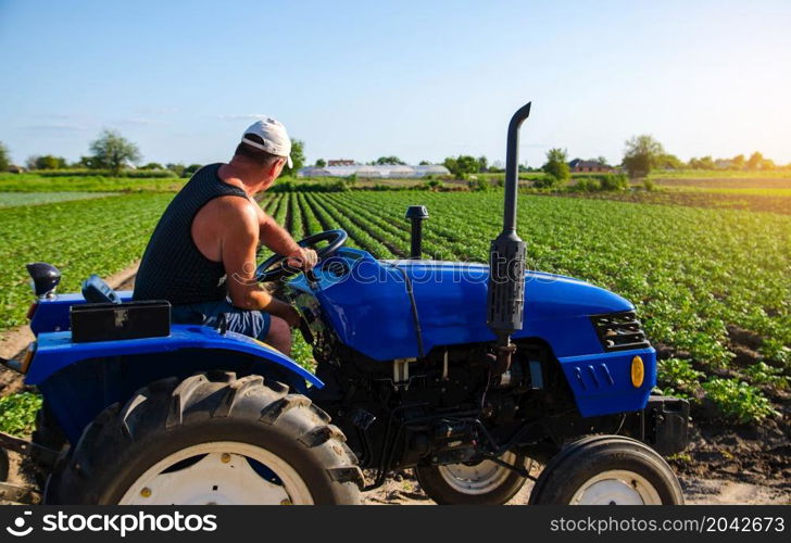 Farmer works in the field with a tractor. Agroindustry and agribusiness. Farm machinery. Crop care, soil quality improvement. Plowing and loosening ground. Field work cultivation. Farming landscape