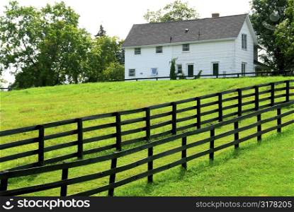Farmhouse with fence among green fields