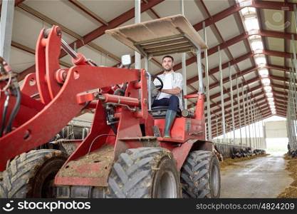 farming, agriculture and people concept - happy young man or farmer driving tractor at farm