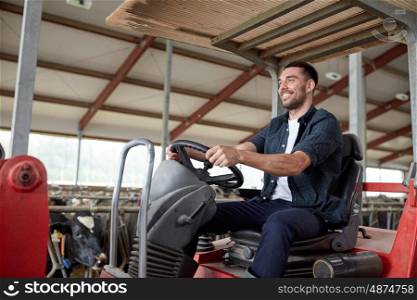farming, agriculture and people concept - happy young man or farmer driving tractor at farm