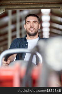 farming, agriculture and people concept - man or farmer driving tractor at farm