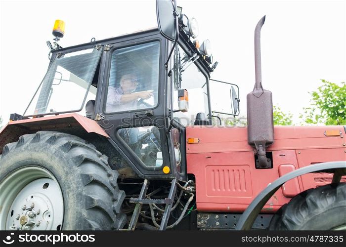 farming, agriculture and people concept - senior man driving tractor at farm