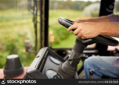 farming, agriculture and people concept - senior man driving tractor at farm. senior man driving tractor at farm