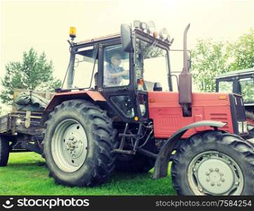 farming, agriculture and people concept - senior man driving tractor at farm. senior man driving tractor at farm