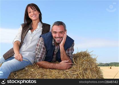 Farming couple sitting on a haystack