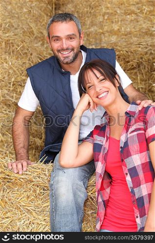 Farming couple sitting on hay
