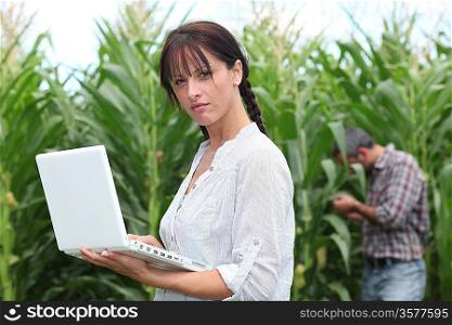 Farming couple with a laptop in a field of corn