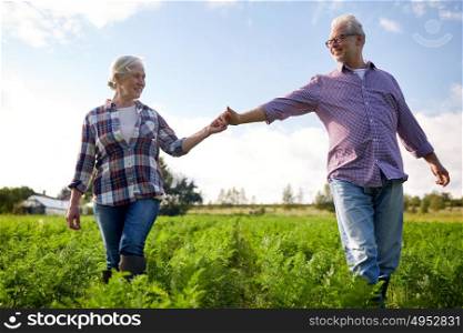 farming, gardening, agriculture and people concept - happy senior couple holding hands at summer farm. happy senior couple holding hands at summer farm