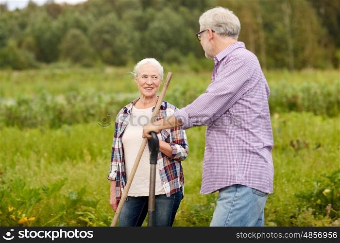 farming, gardening, agriculture and people concept - happy senior couple with garden tools working at farm