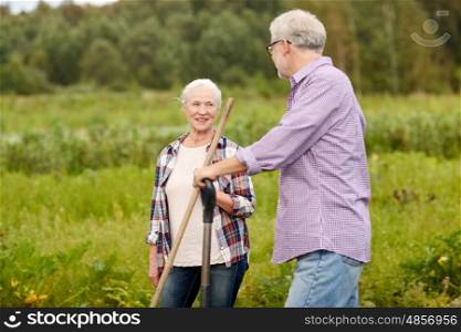 farming, gardening, agriculture and people concept - happy senior couple with garden tools working at farm
