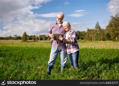 farming, gardening, agriculture and people concept - happy senior couple with tablet pc computer at summer farm. happy senior couple with tablet pc at summer farm