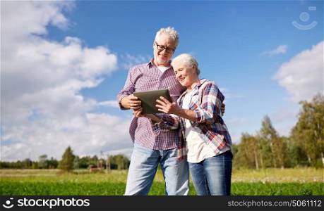 farming, gardening, agriculture and people concept - happy senior couple with tablet pc computer at summer farm. happy senior couple with tablet pc at summer farm