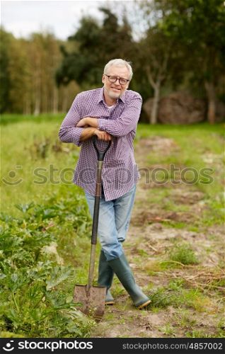farming, gardening, agriculture and people concept - happy senior man with shovel at garden or farm