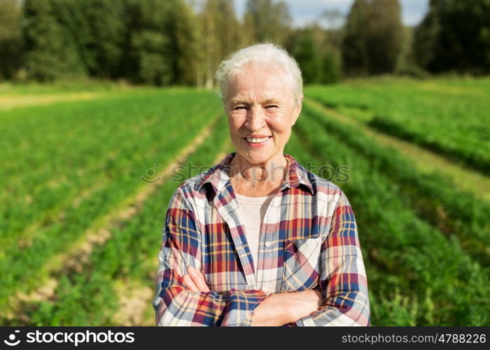 farming, gardening, agriculture and people concept - happy senior woman at farm