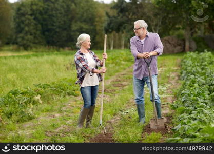 farming, gardening, agriculture and people concept - senior couple with shovels at garden or farm. senior couple with shovels at garden or farm