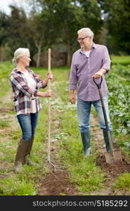 farming, gardening, agriculture and people concept - senior couple with shovels at garden or farm. senior couple with shovels at garden or farm