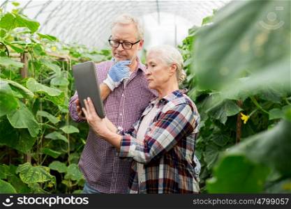 farming, gardening, agriculture and people concept - senior couple with tablet pc computer at farm greenhouse
