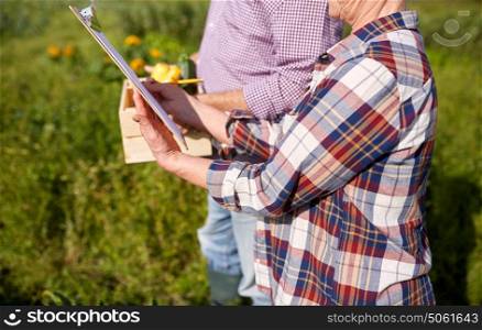 farming, gardening, agriculture, harvest and people concept - happy senior couple with squashes and clipboard at farm. happy senior couple with squashes at farm