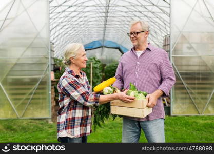 farming, gardening, agriculture, harvesting and people concept - senior couple with box of vegetables at farm greenhouse