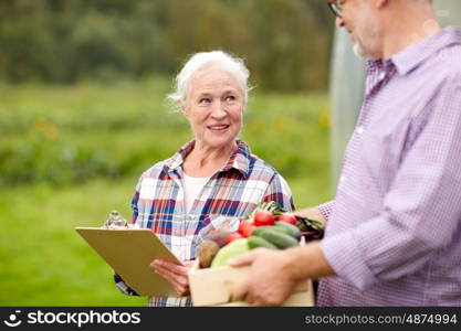 farming, gardening, agriculture, harvesting and people concept - senior couple with box of vegetables and clipboard at farm