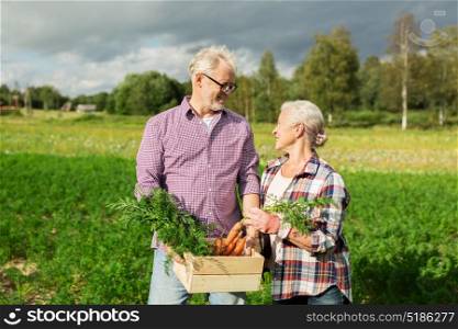 farming, gardening, agriculture, harvesting and people concept - senior couple with box of carrots at farm. senior couple with box of carrots on farm