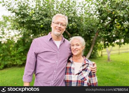 farming, gardening, old age and people concept - happy senior couple hugging at summer garden