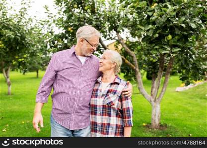 farming, gardening, old age and people concept - happy senior couple hugging at summer garden
