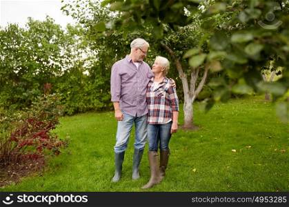 farming, gardening, old age and people concept - happy senior couple hugging at summer garden. happy senior couple hugging at summer garden