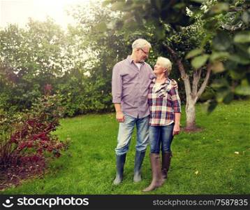 farming, gardening, old age and people concept - happy senior couple hugging at summer garden. happy senior couple hugging at summer garden