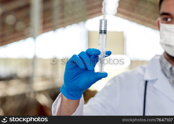 farming, medicine and animal husbandry concept - close up of veterinarian or doctor hand with vaccine in syringe on farm wearing medical mask for protection from virus. veterinarian in mask with syringe on dairy farm