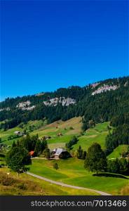 Farmland cottage, grass hill and mountain of Marbach town, Entlebuch UNESCO Biosphere Reserve in central Switzerland