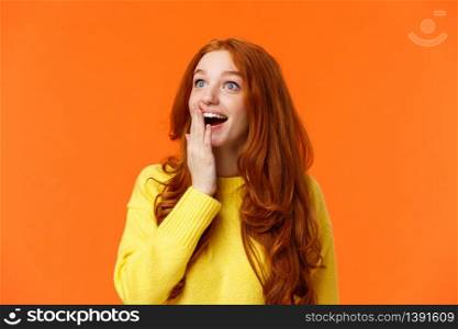 Fascinated and amiring cute redhead woman looking impressed and excited at upper left corner, smiling see breathtaking view, cover opened mouth palm thrilled, losing speech happy, orange background.. Fascinated and amiring cute redhead woman looking impressed and excited at upper left corner, smiling see breathtaking view, cover opened mouth palm thrilled, losing speech happy, orange background