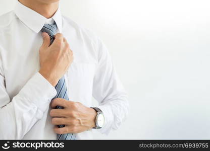 fashion and clothing concept - close up of business man in shirt dressing up and adjusting tie on neck