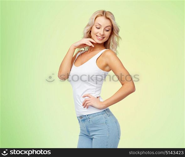 fashion and people concept - happy smiling beautiful young woman in white top and jeans with blonde hair over green background. happy smiling young woman with blonde hair