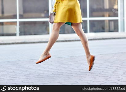 fashion and people concept - happy young woman or teenage girl legs flying above pavement on city street. young woman or teenage girl legs on city street