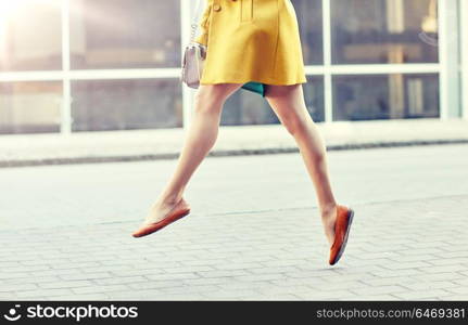 fashion and people concept - happy young woman or teenage girl legs flying above pavement on city street. young woman or teenage girl legs on city street