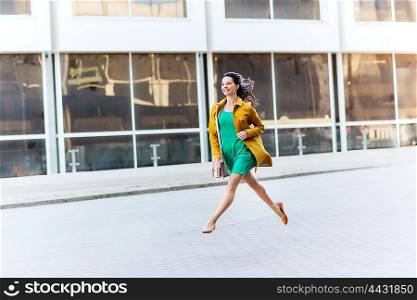 fashion and people concept - happy young woman or teenage girl running and jumping high on city street. happy young woman or teenage girl on city street