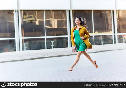 fashion and people concept - happy young woman or teenage girl running and jumping high on city street. happy young woman or teenage girl on city street