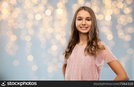 fashion and people concept - smiling young teenage girl in party dress over festive lights background. smiling teenage girl in party dress over lights
