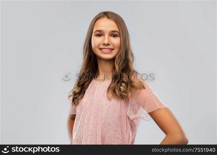 fashion and people concept - smiling young teenage girl in party dress over grey background. smiling young teenage girl in party dress