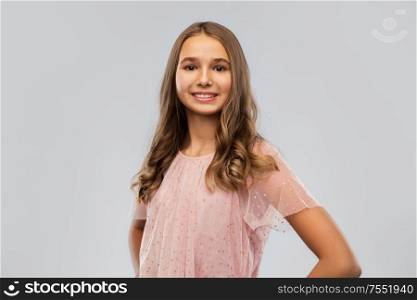 fashion and people concept - smiling young teenage girl in party dress over grey background. smiling young teenage girl in party dress