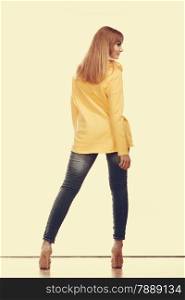 Fashion and people concept. Woman full length in denim trousers high heels shoes yellow shirt back view