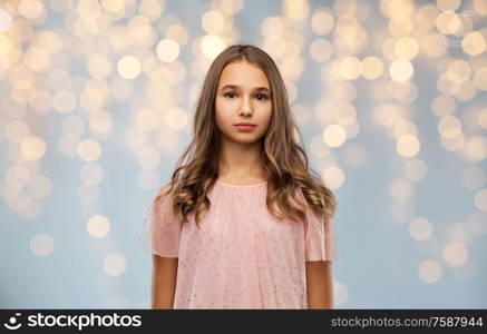 fashion and people concept - young teenage girl in party dress over festive lights background. teenage girl in party dress over festive lights